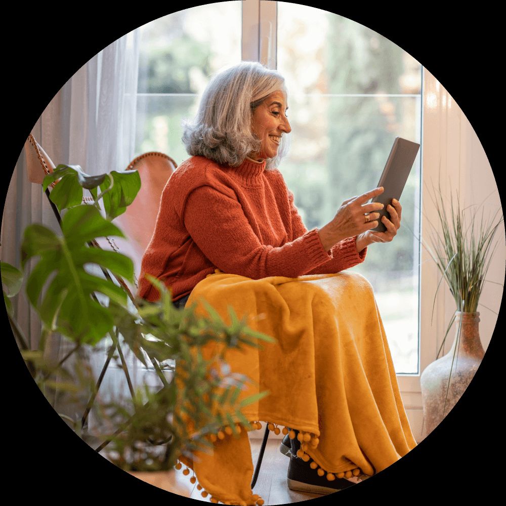 lady with blanket looking at a tablet.